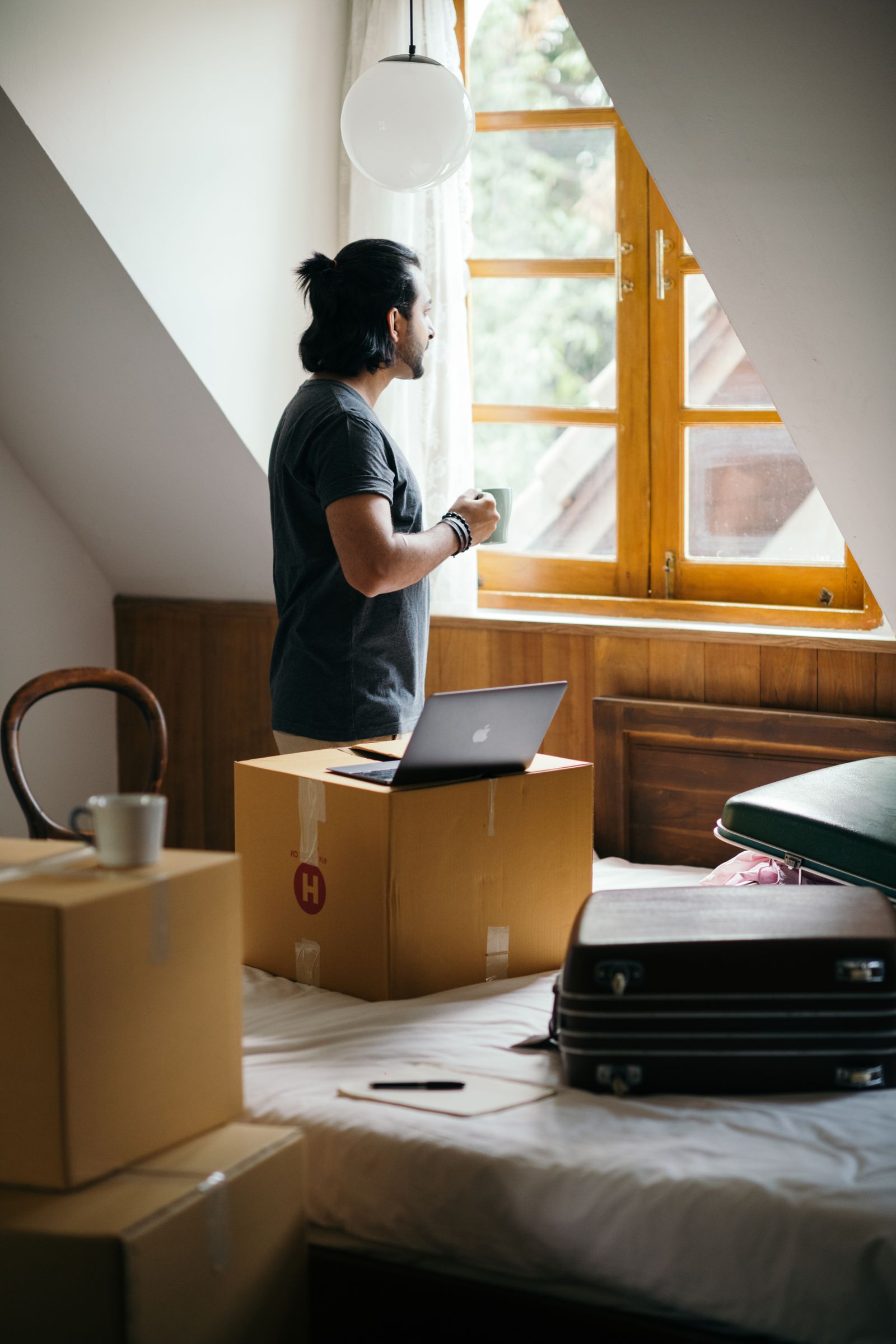 A person taking a quiet moment by the window while unpacking at home
